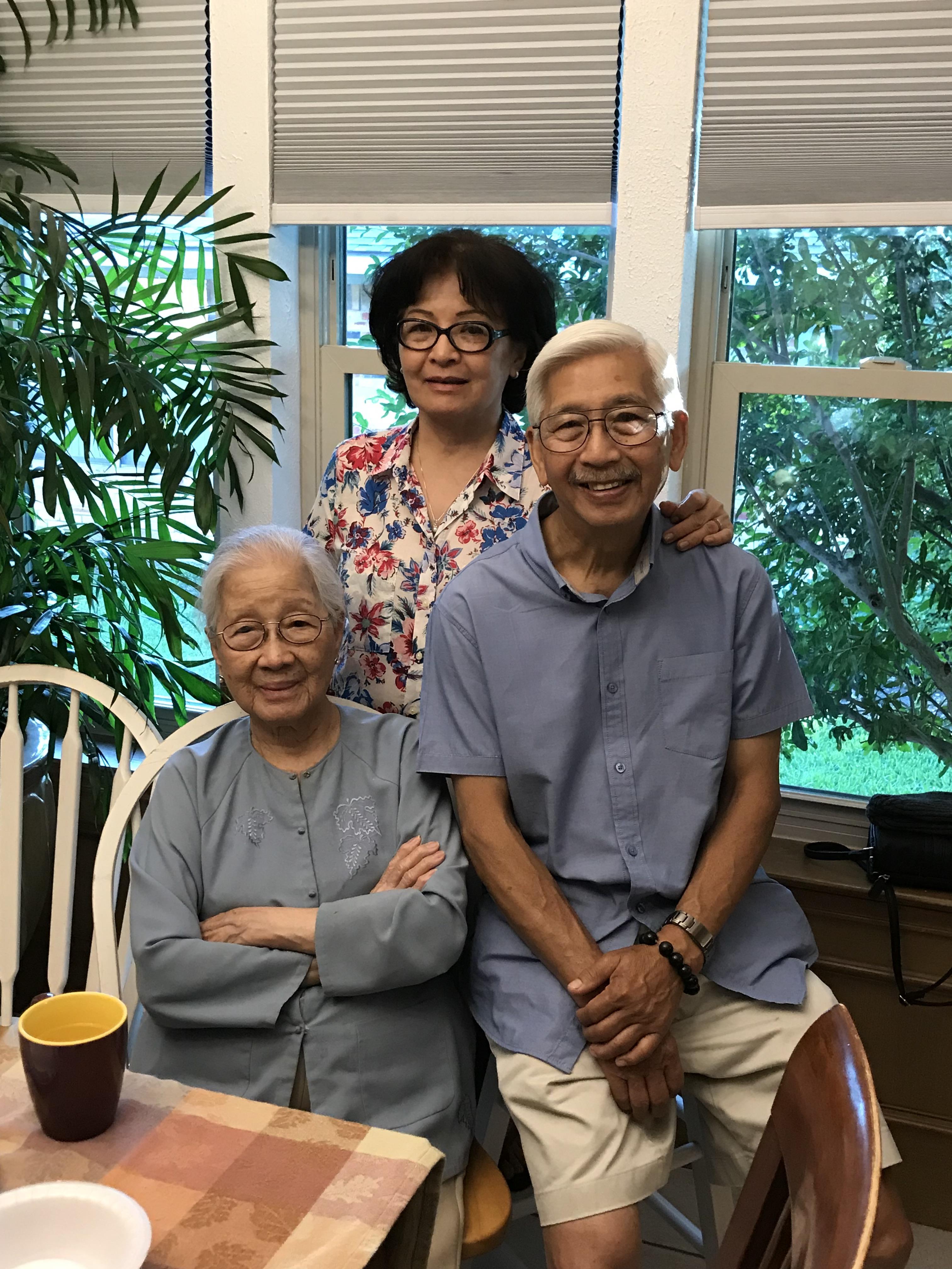 Three individuals gather in a bright room, sharing smiles and moments in a warm atmosphere.