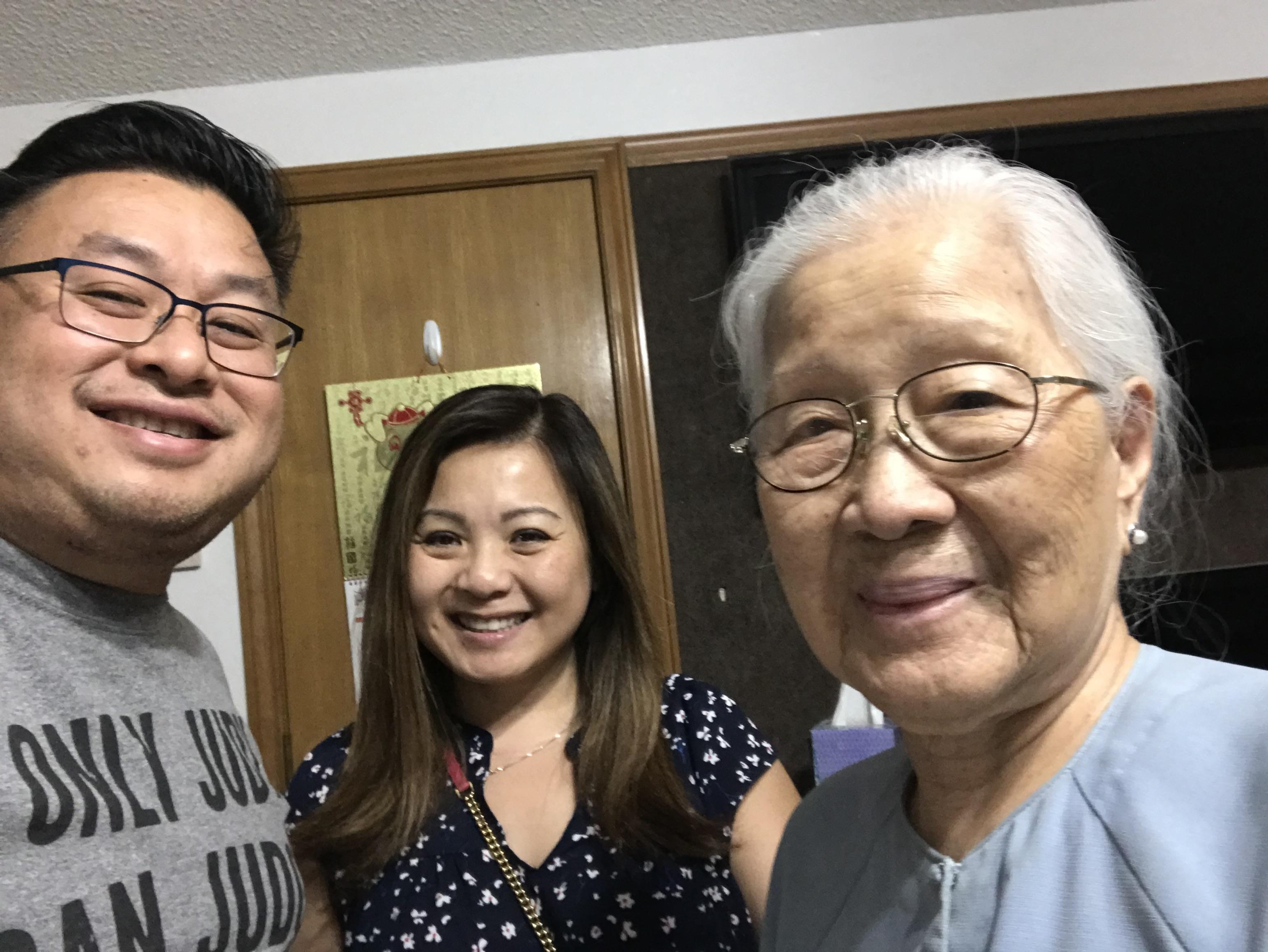 Three family members smile together while enjoying their time at home in the evening.