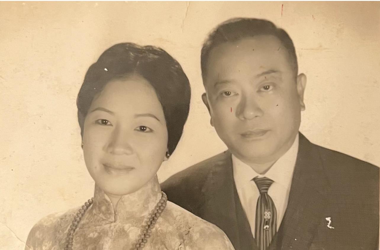 A man and woman stand together, looking at the camera with smiles.