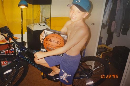 A boy on a bike holding a basketball