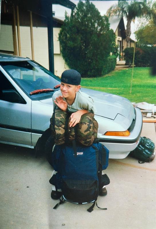 A boy sitting on a backpack