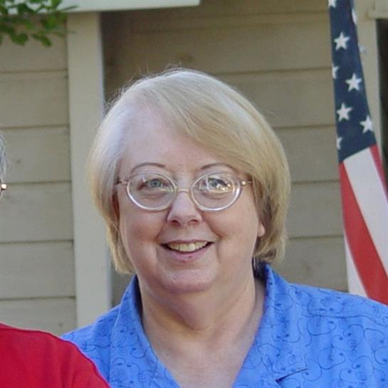 A woman wearing glasses and smiling
