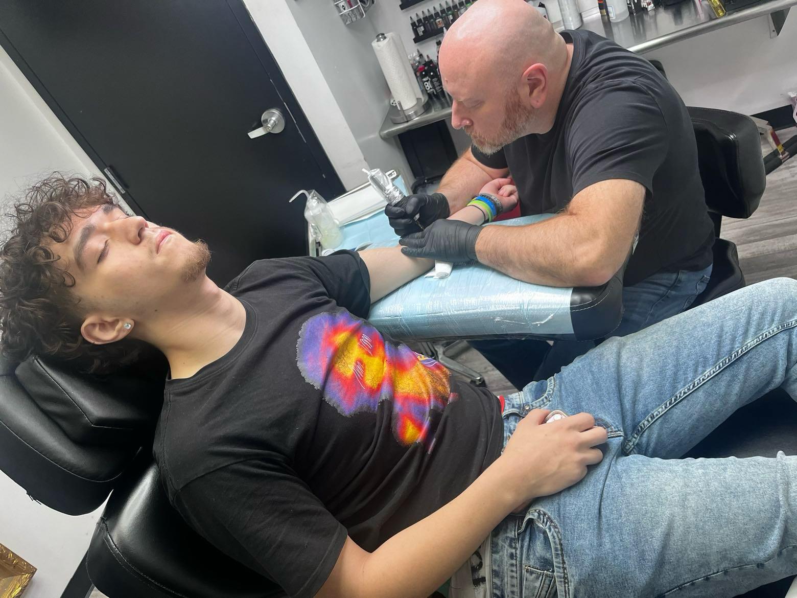 A man getting a tattoo on a man's arm