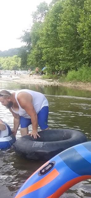 Group of people relax and float on inner tubes in a river during a warm summer afternoon.