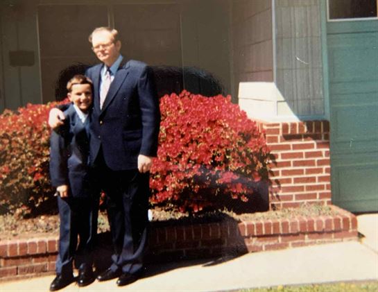 A man and boy standing in front of a house