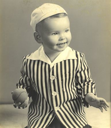 A baby wearing a striped outfit holding a ball