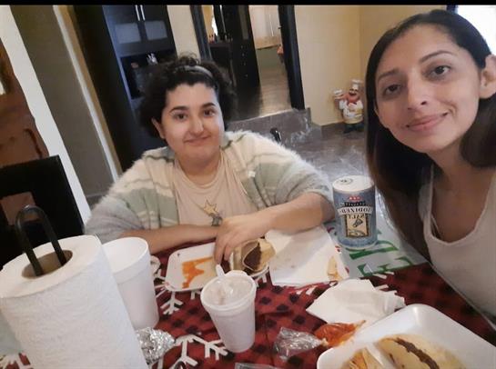 Two women sitting at a table with food and drinks