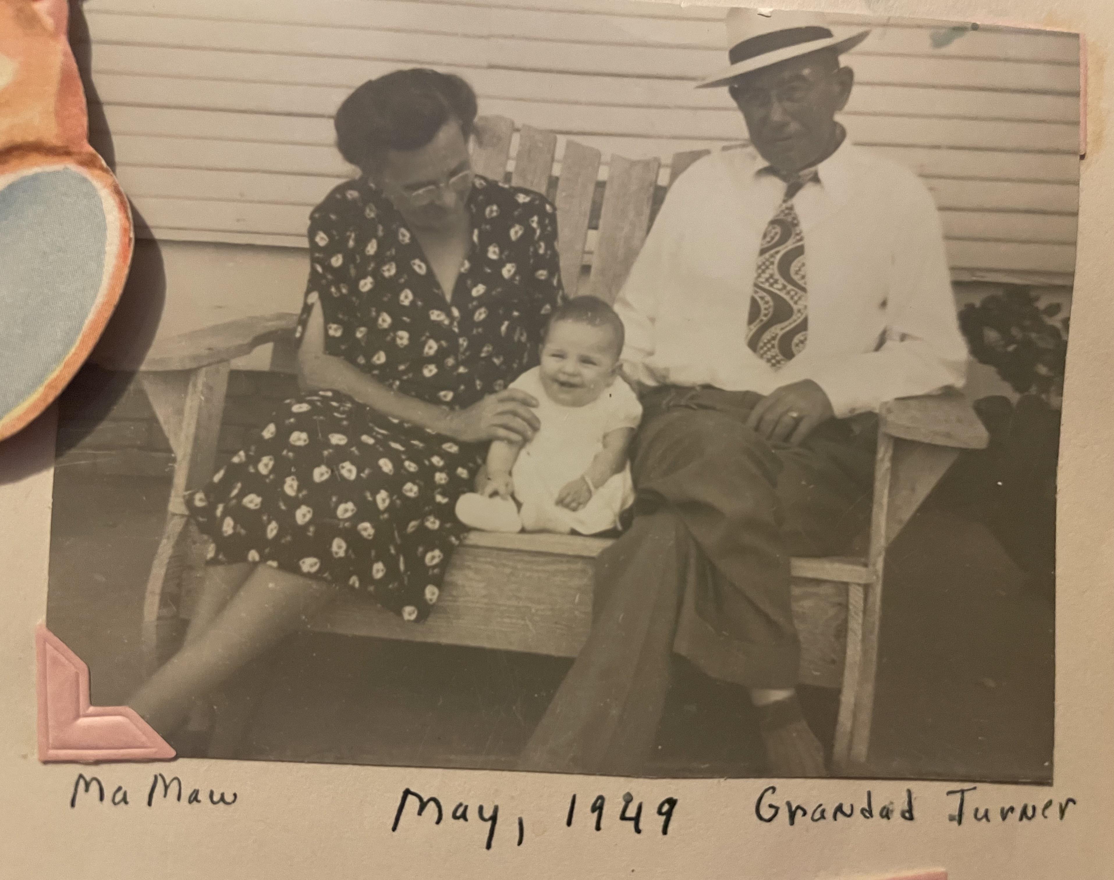 A couple sits on a swing holding a baby on a warm day in May 1949. They are enjoying time together.