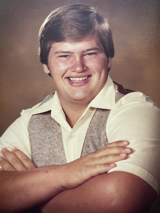 A man smiling with arms crossed