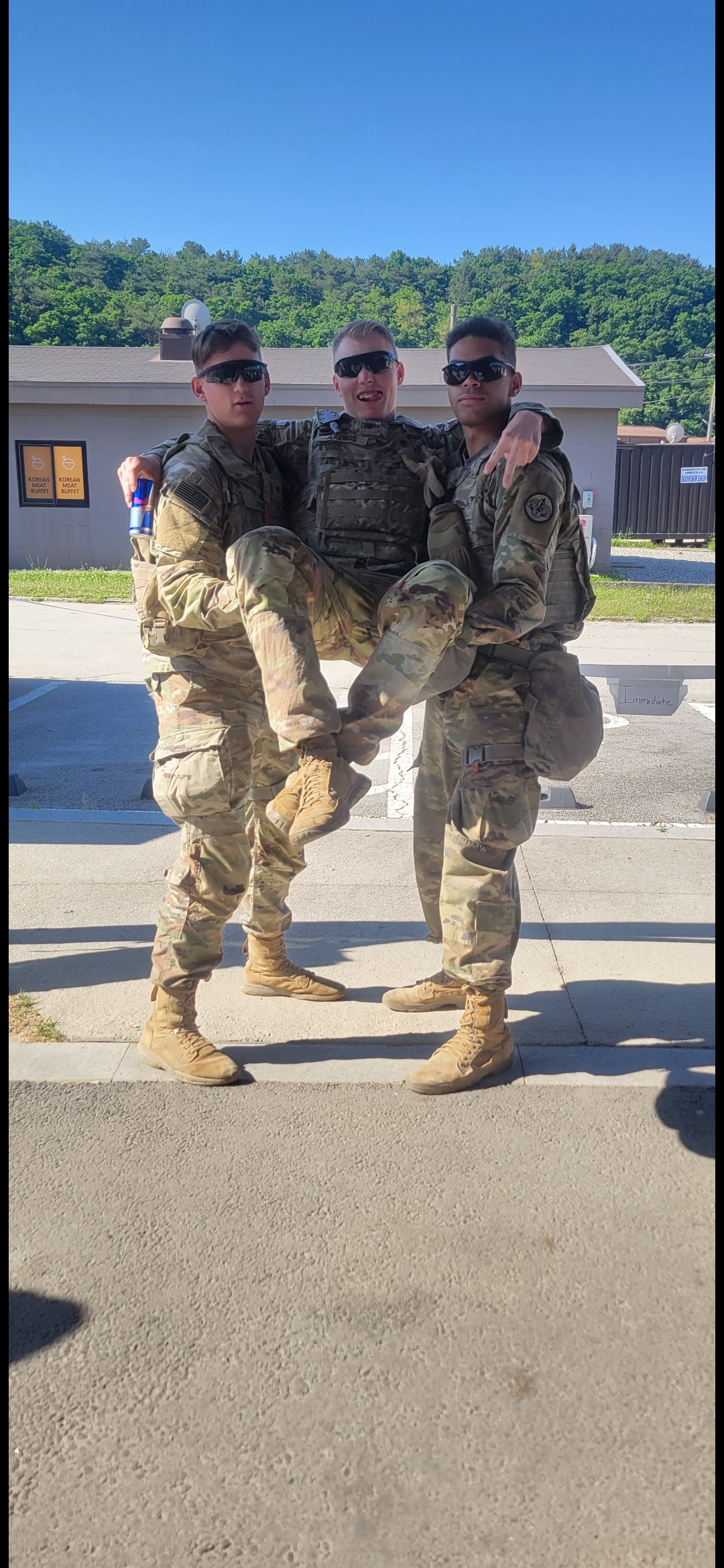 Three soldiers work together to lift a fourth soldier in training at a military base.