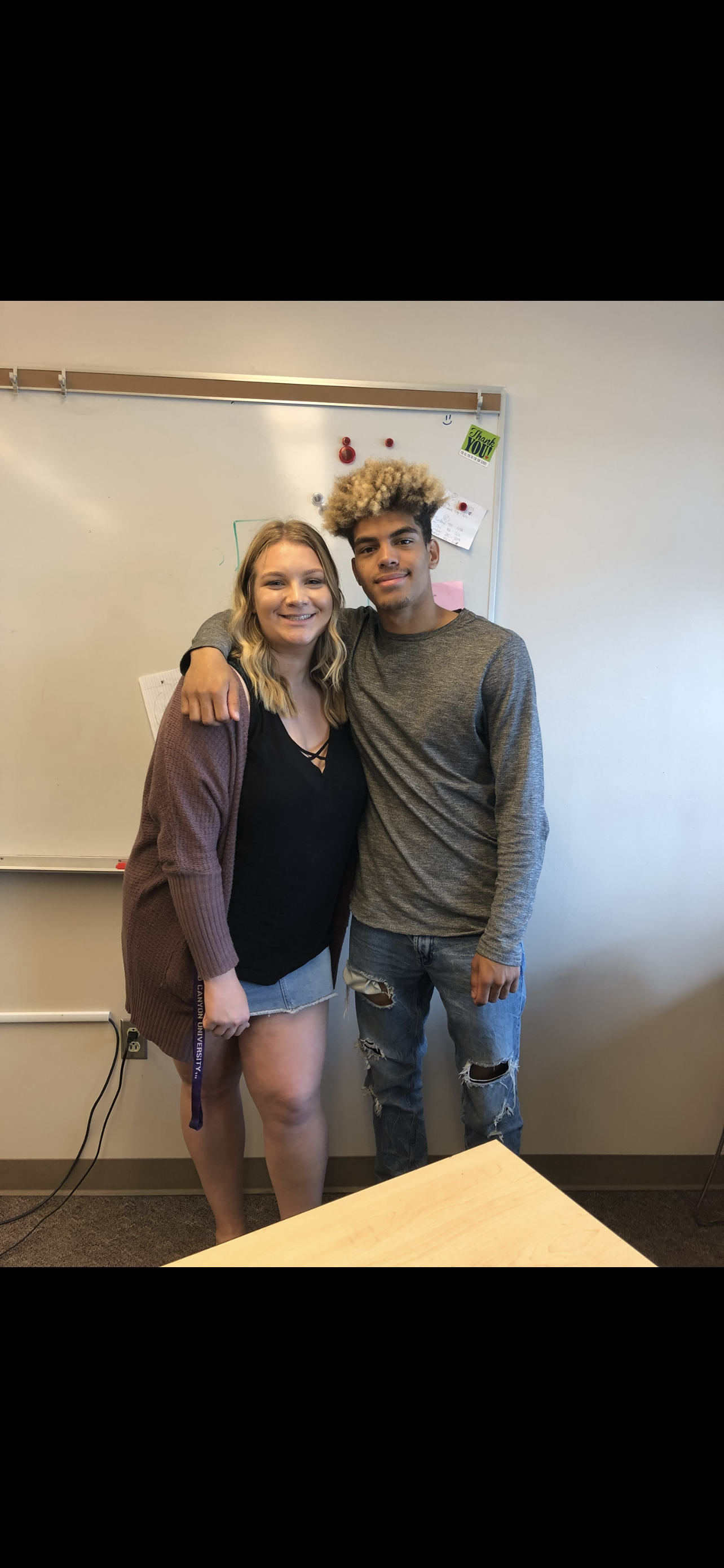 Two students stand close in a classroom, smiling after an event during summer school.