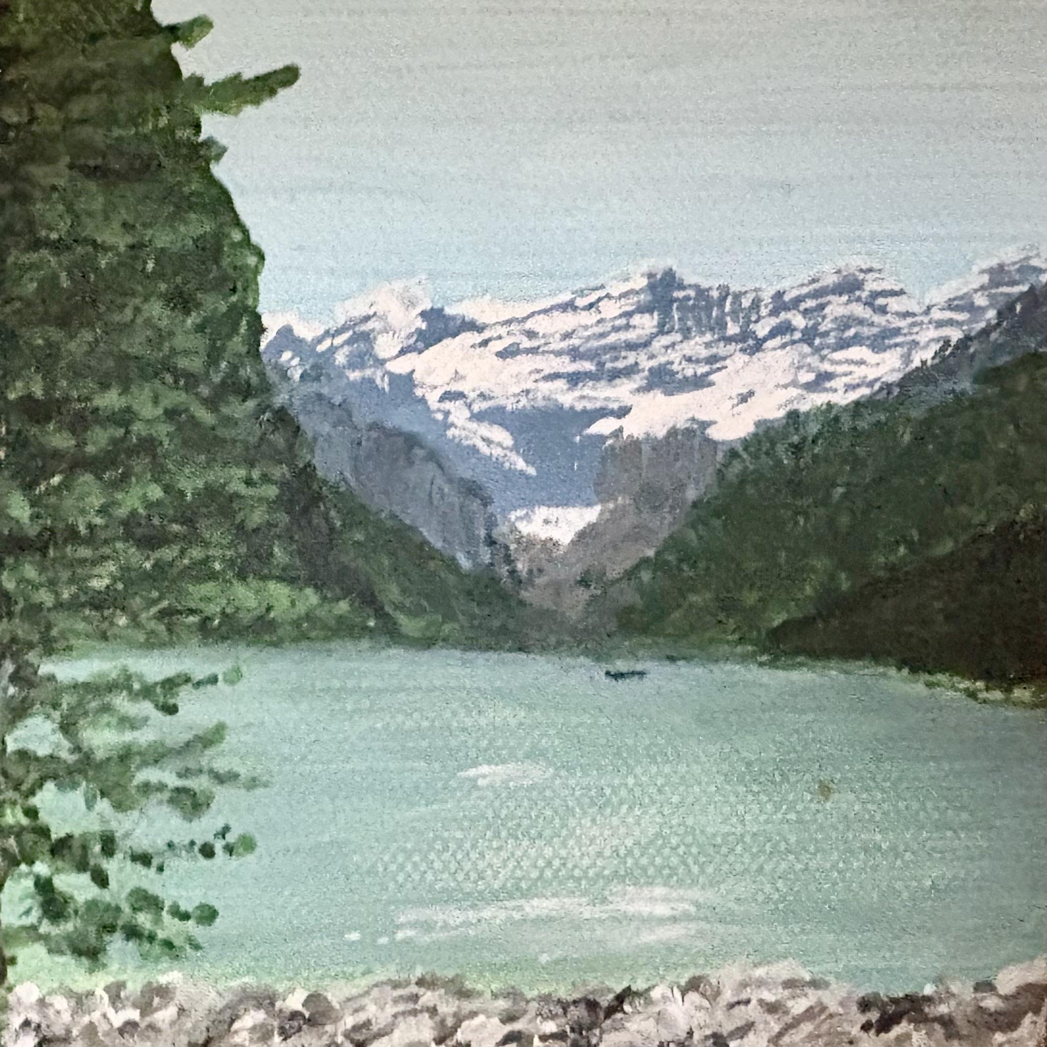 A lake sits between mountains with trees around it. Snow covers the peaks in the distance.