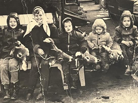 A group of children sitting on a chair with deer
