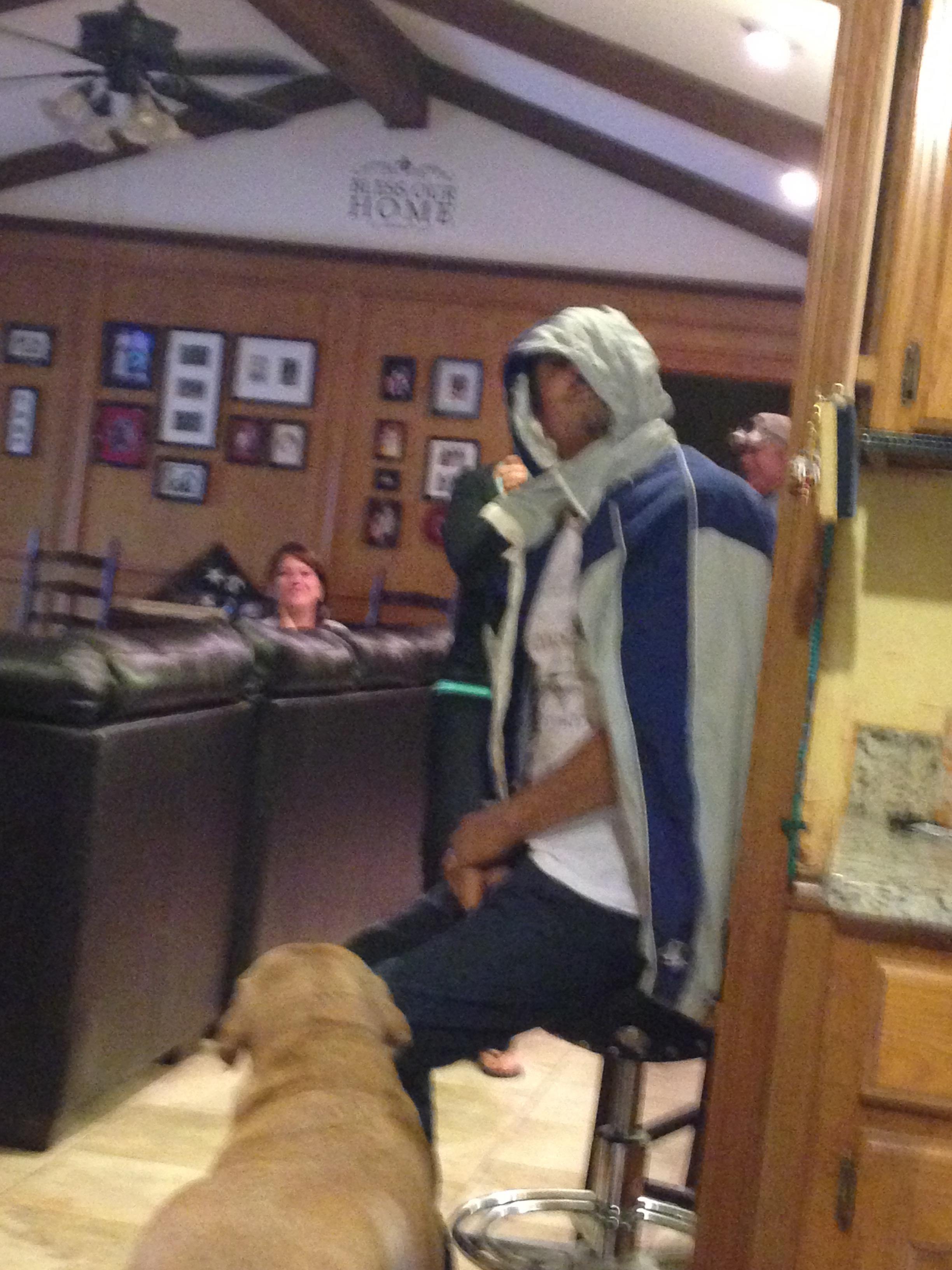 People are sitting in a living room with a dog while one person wears a hoodie.