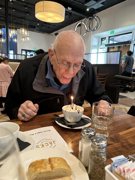 An old man blowing out a candle on a cup