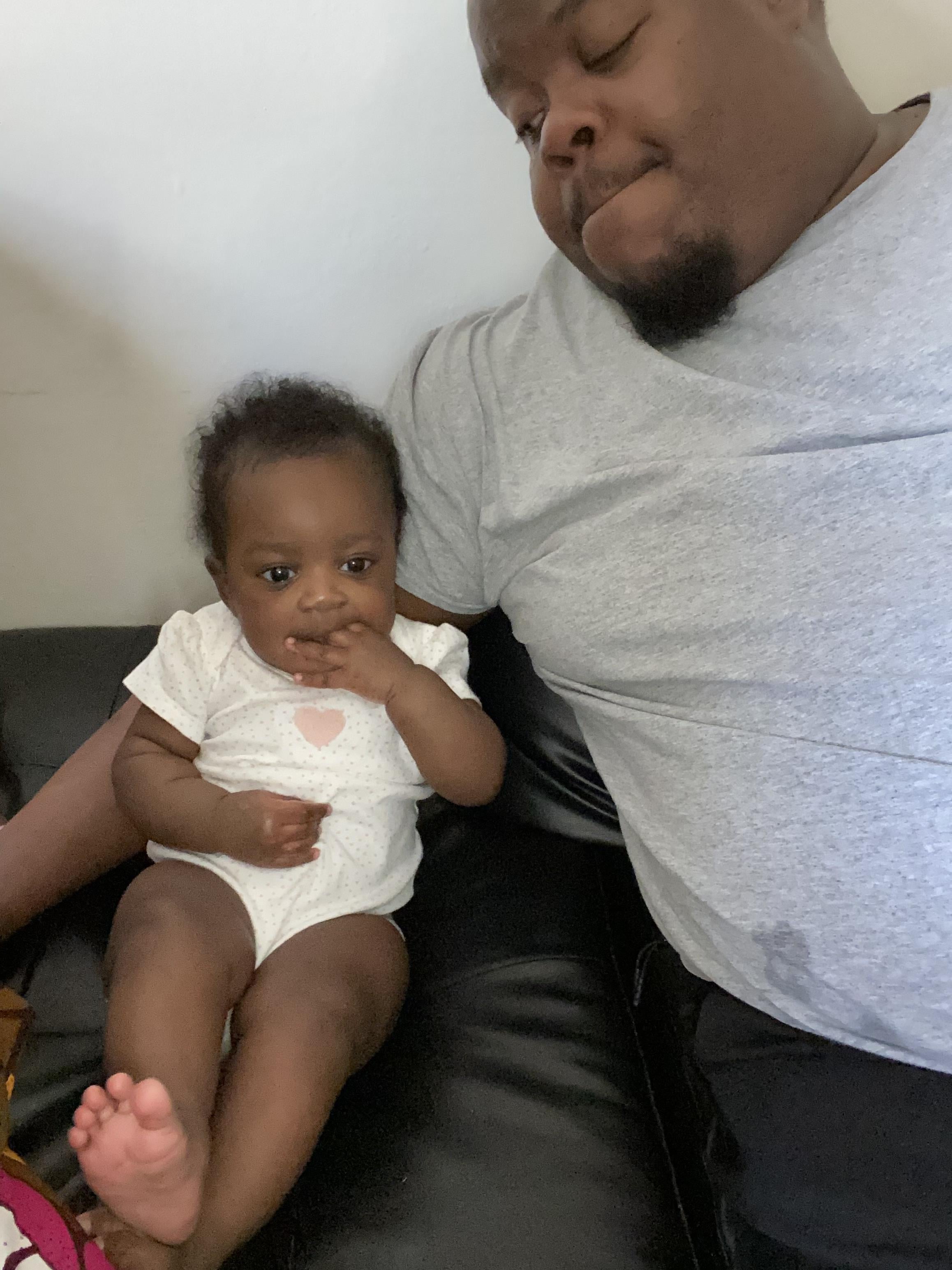 A man sitting on a couch holding a baby