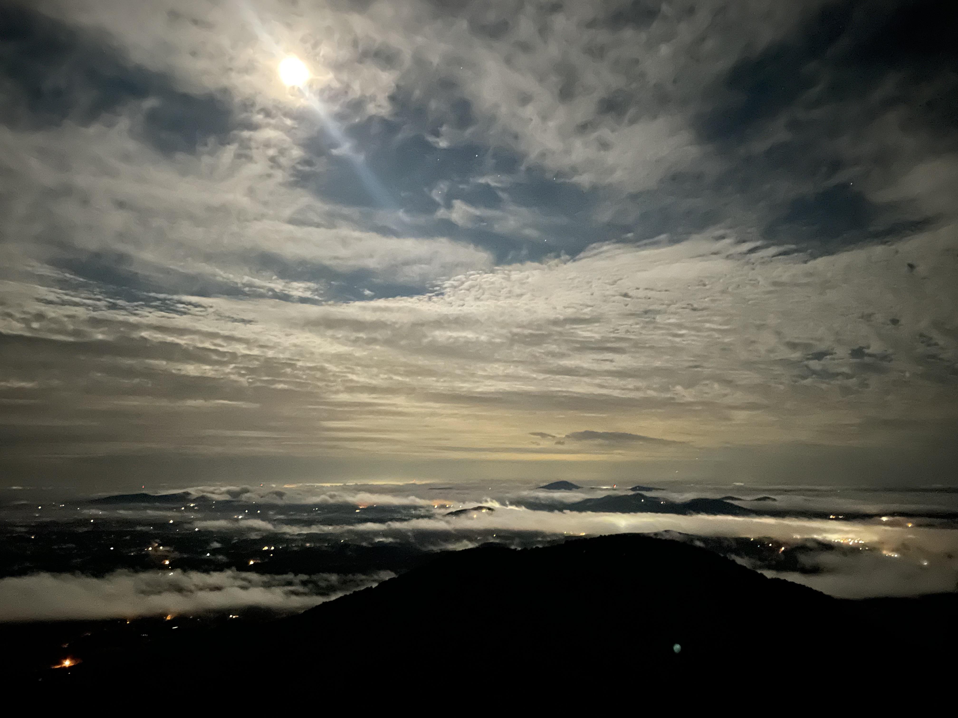 A sun shining through clouds over a valley