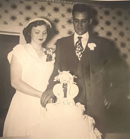 A man and woman standing next to a wedding cake