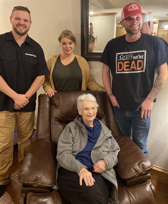 A group of people standing around an old woman in a chair
