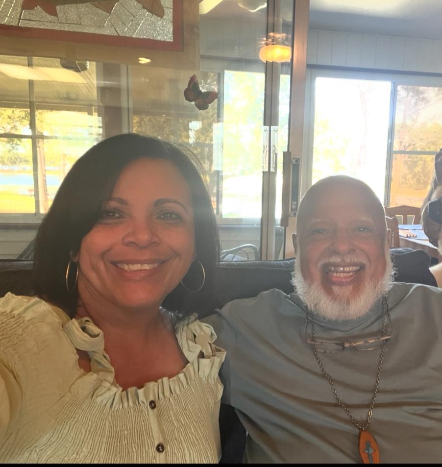 Two friends smile and laugh together while sitting in a cafe, enjoying their time.
