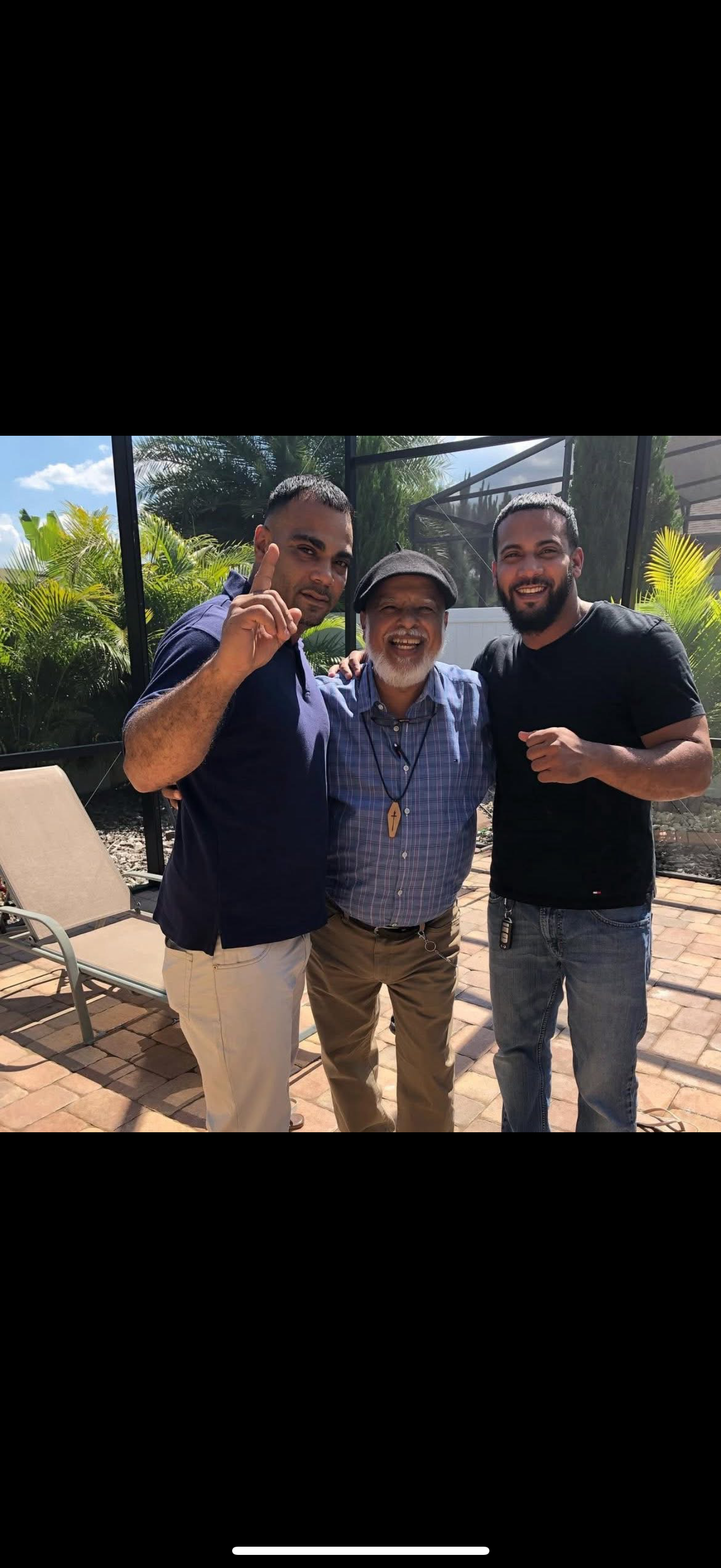 Two young men stand next to an older man, smiling and enjoying their time together outdoors.