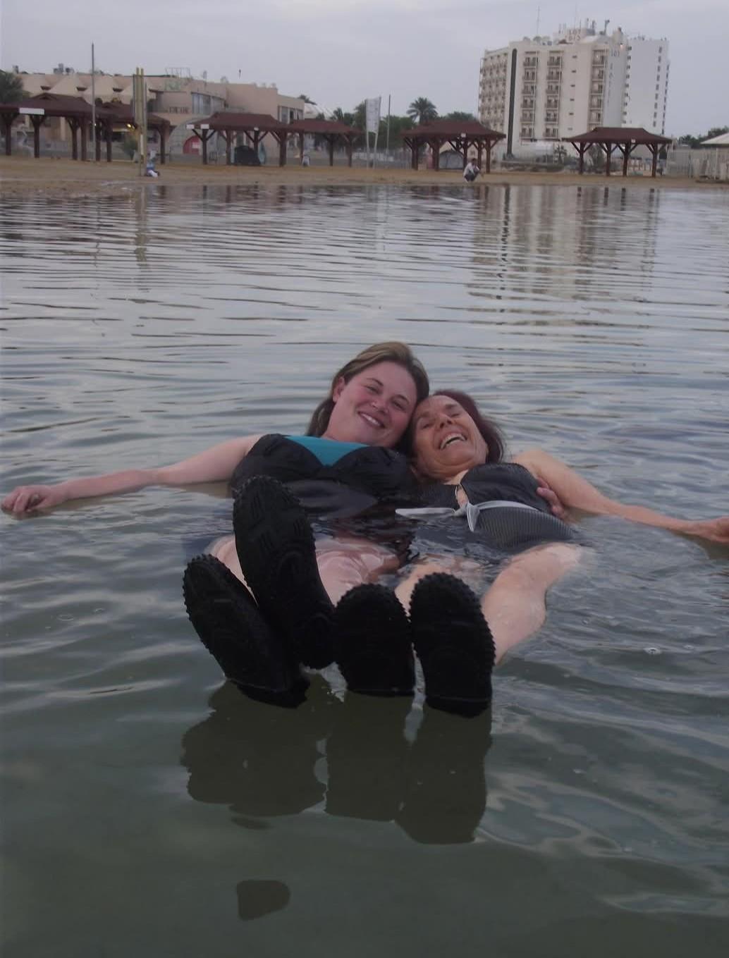 Two friends relax and float in shallow water while enjoying their time at the beach.