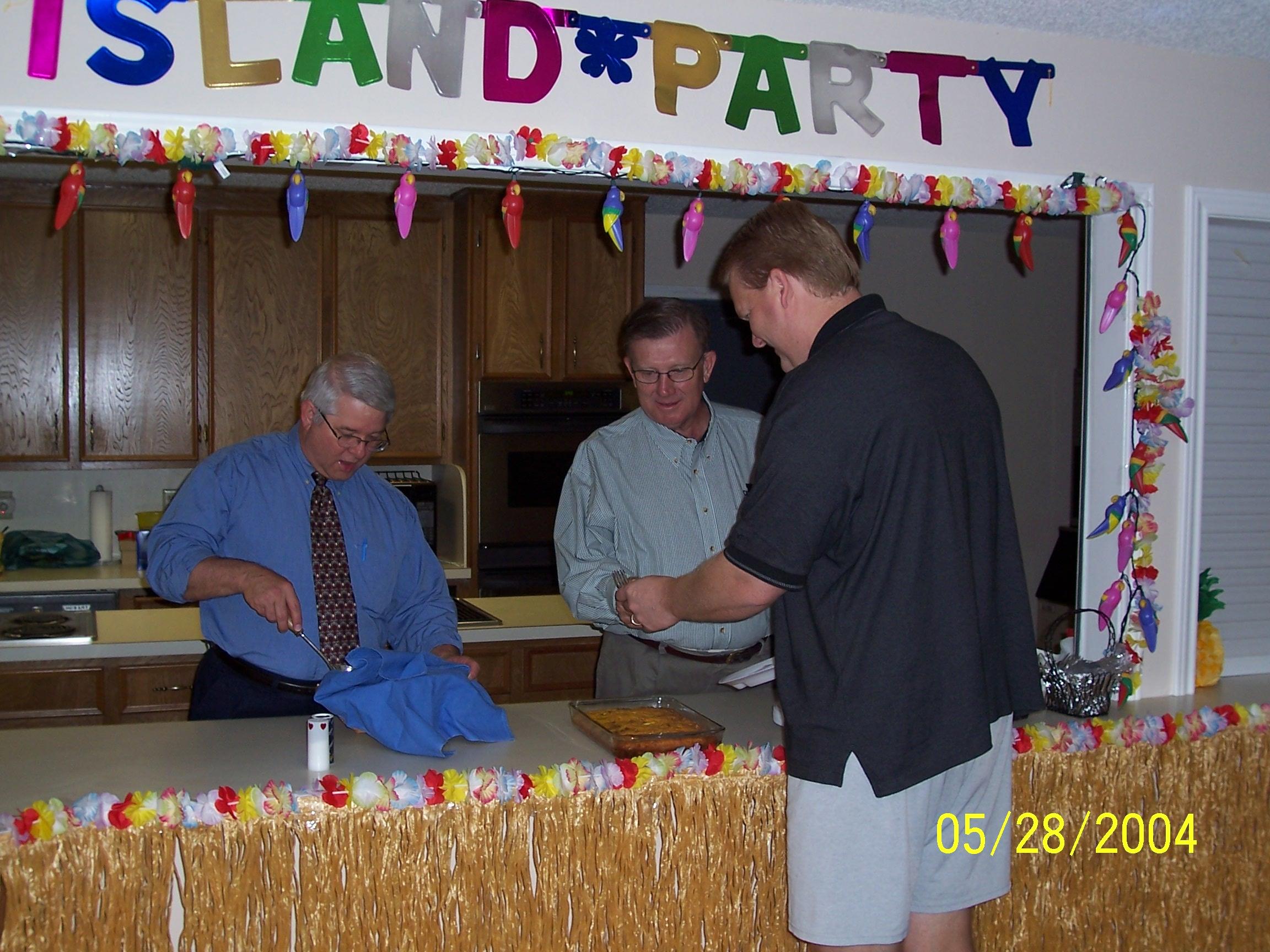 People gather at a buffet table for an island party on May 28 in a community center setting.