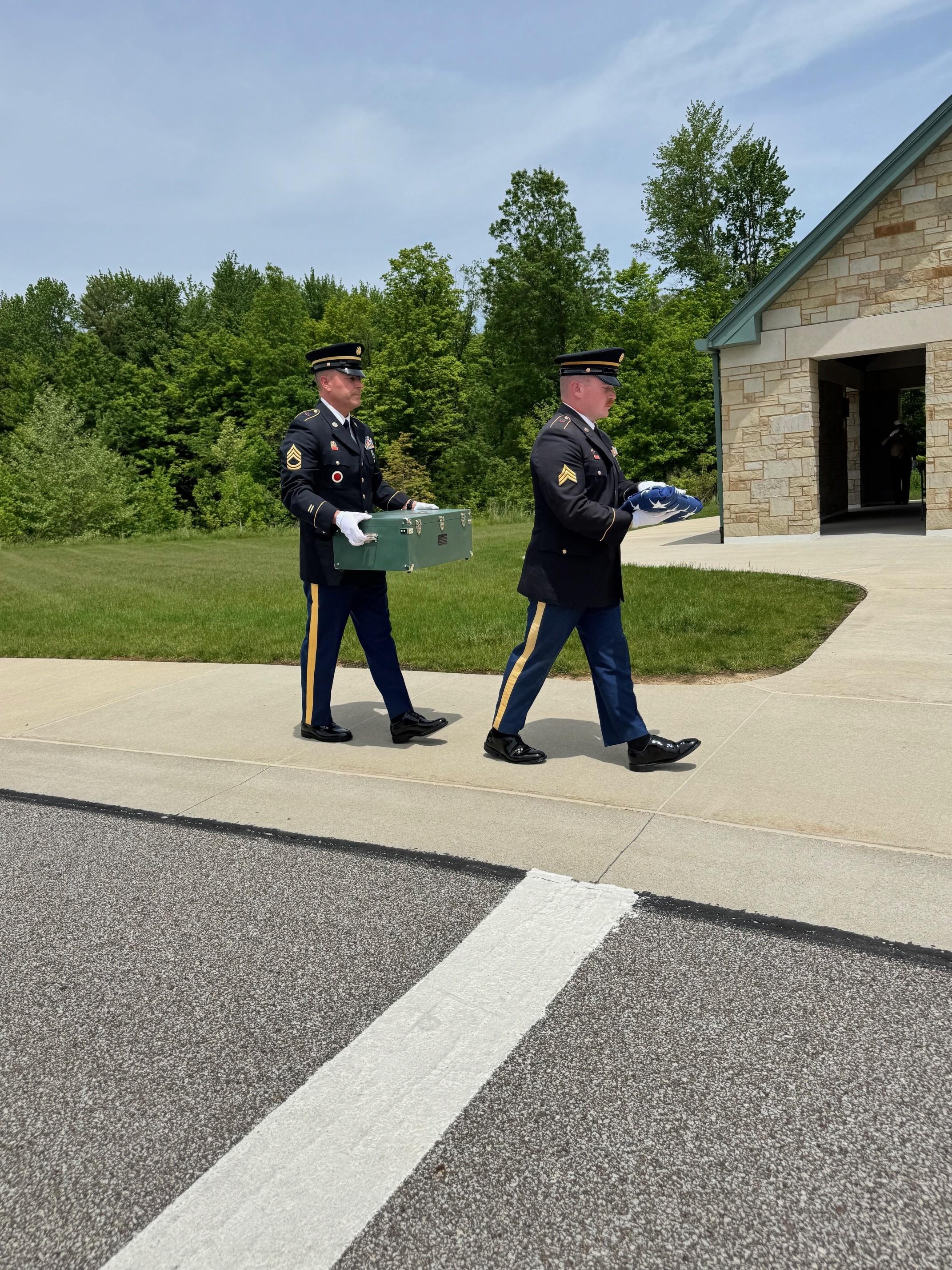 Two men in uniform walking on a sidewalk