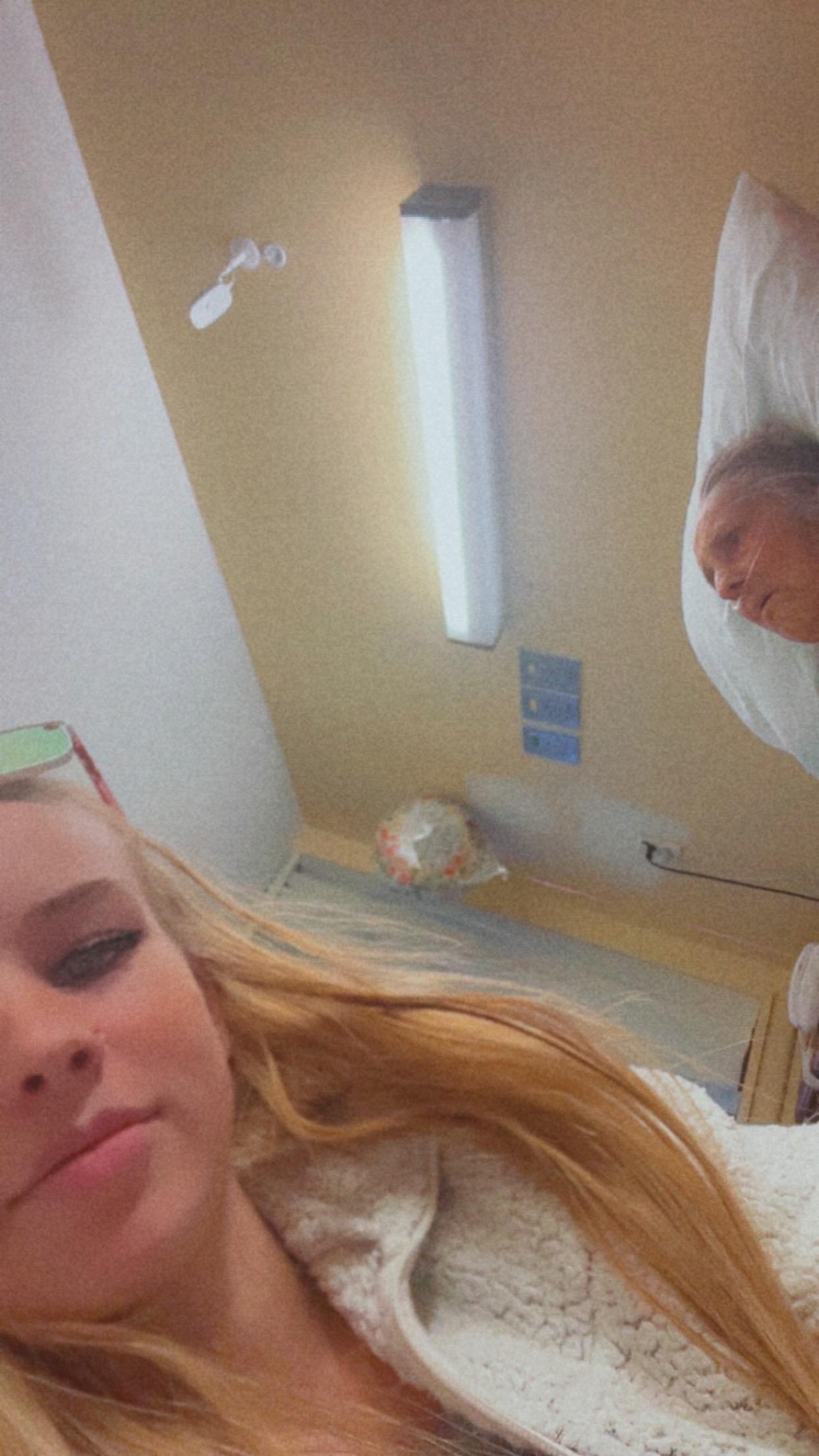 Two individuals are in a hospital room sharing a moment during the day.