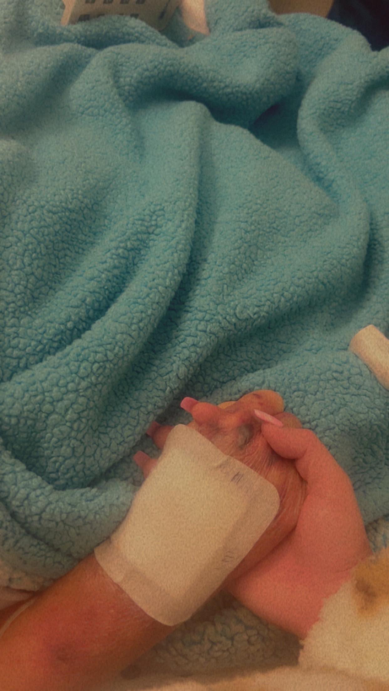 Hands are wiping a small clear bottle on a soft blue blanket while preparing for use.