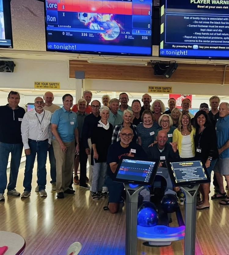 A large group of people stands together at a bowling alley during a fun evening event.