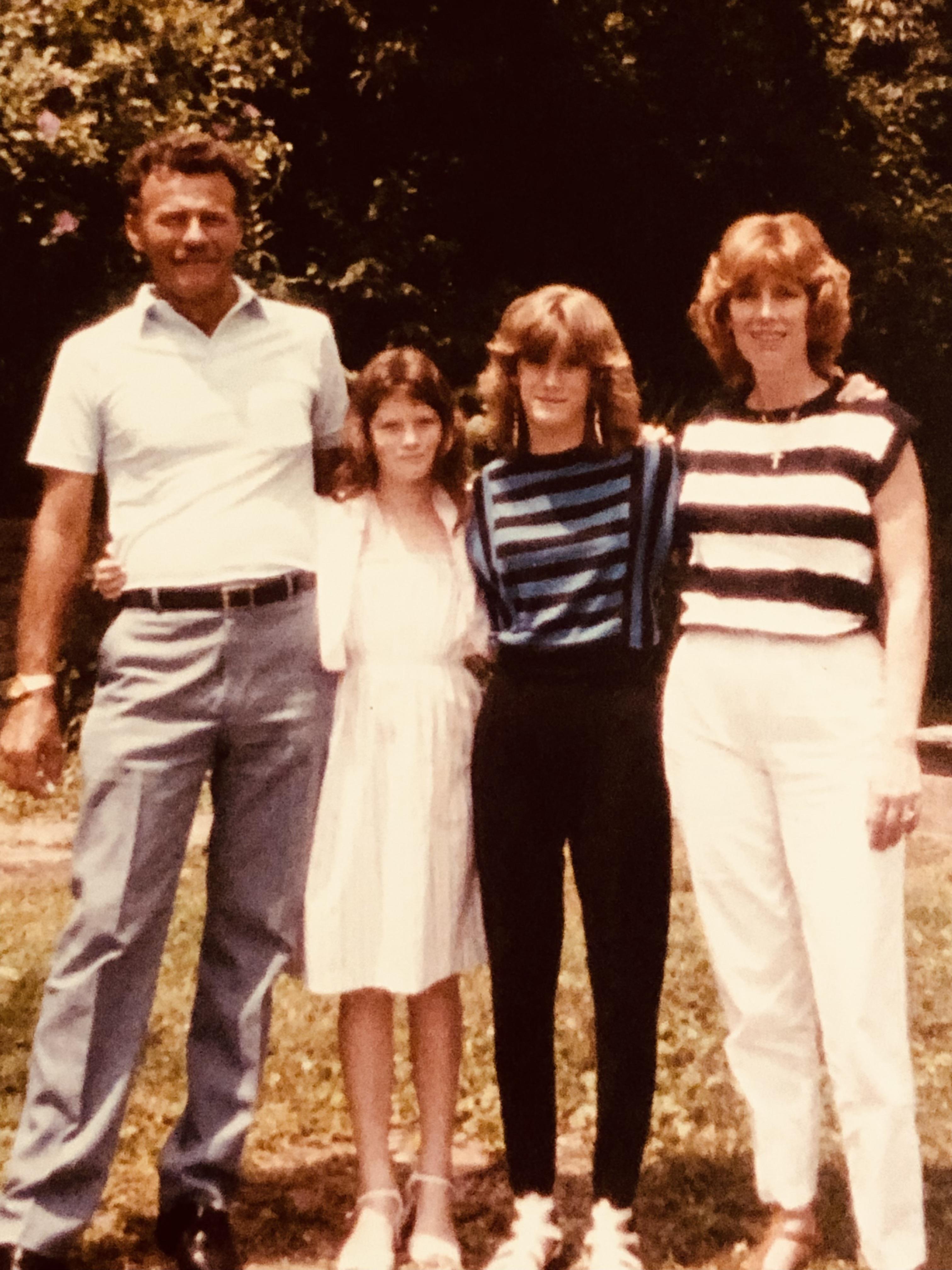 Four people stand together in a park, enjoying time with each other on a sunny day.