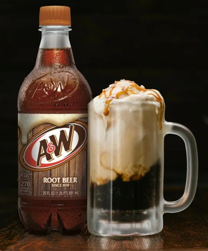 A root beer float is in a clear glass mug next to a bottle of A&W root beer.