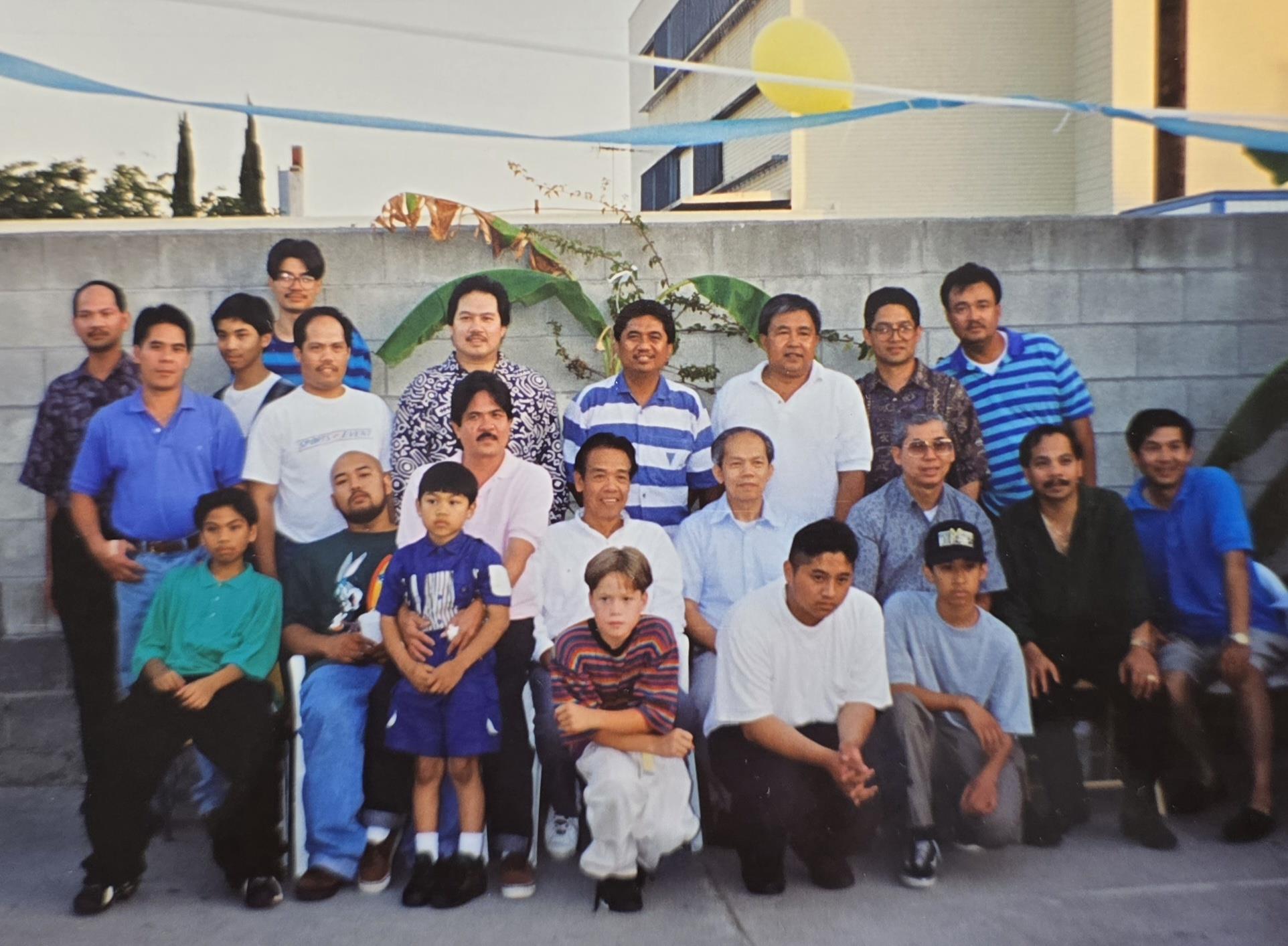 A large group of men, women, and children are standing and sitting together for a celebration.