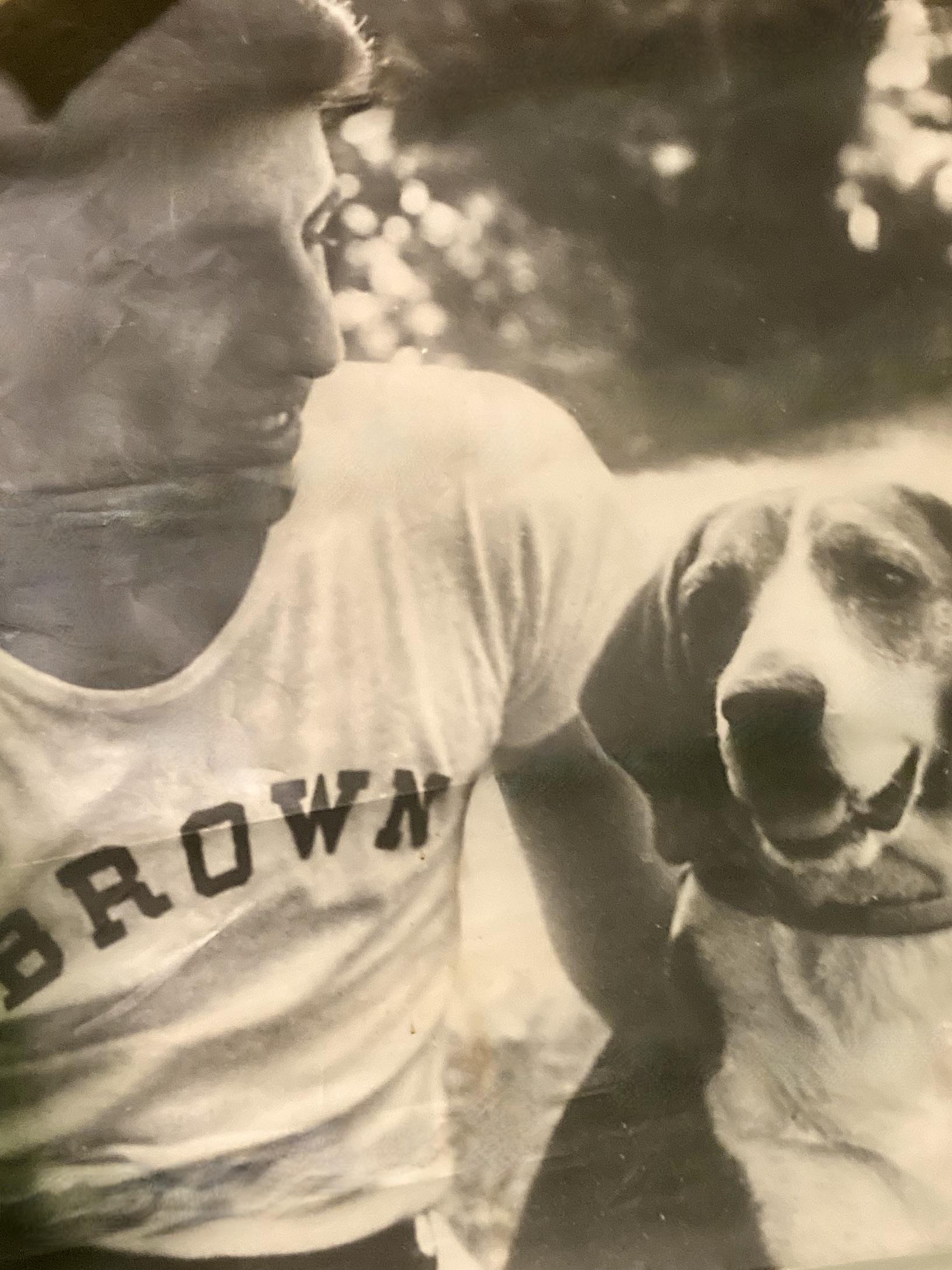 A man enjoys time with a dog in a grassy area on a sunny afternoon. Both look happy.