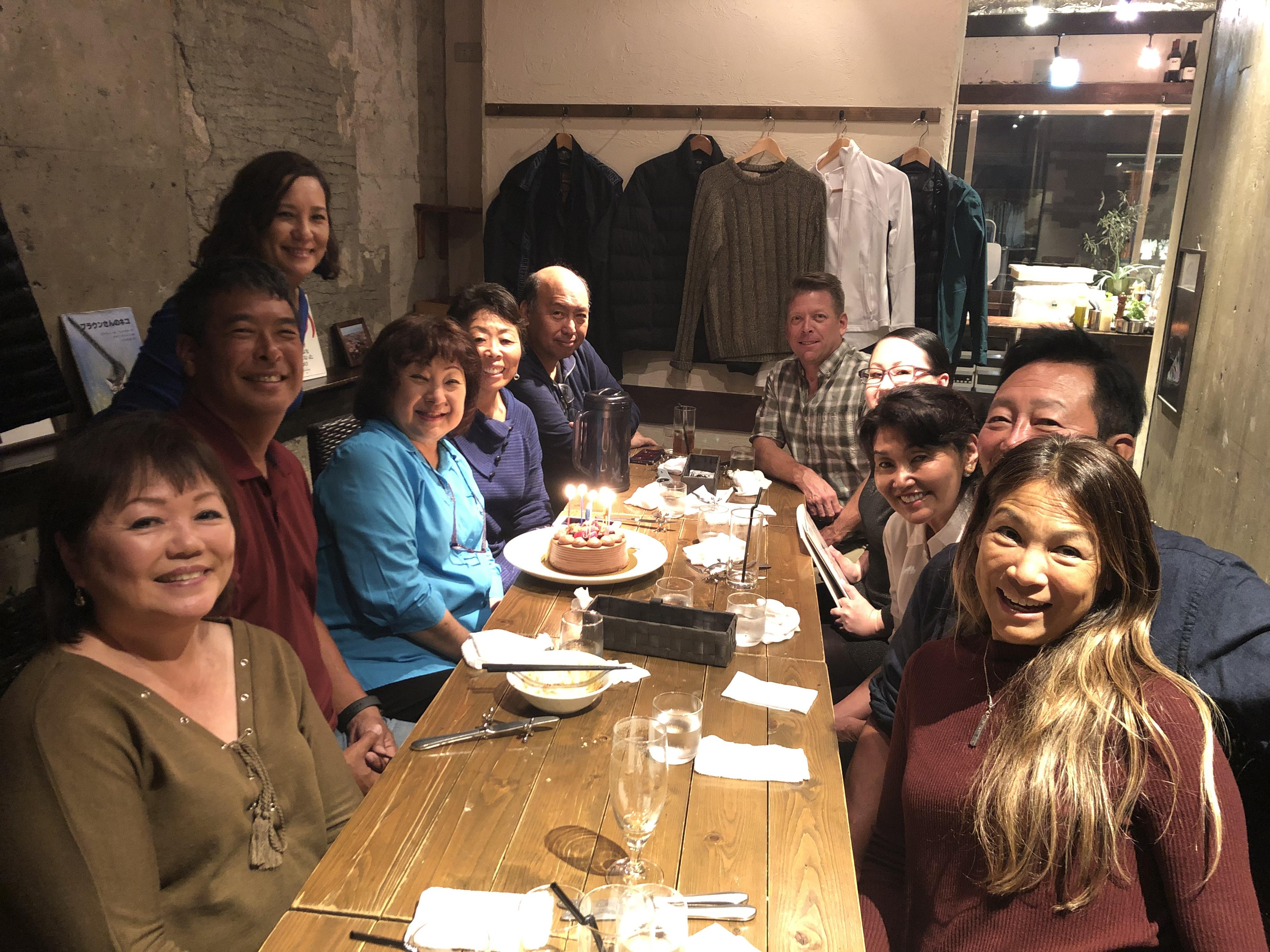 A group of people sitting at a table with a cake