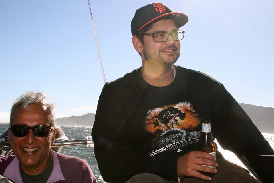 Two people sit on a boat and enjoy drinks while taking in the sunny day and ocean view.