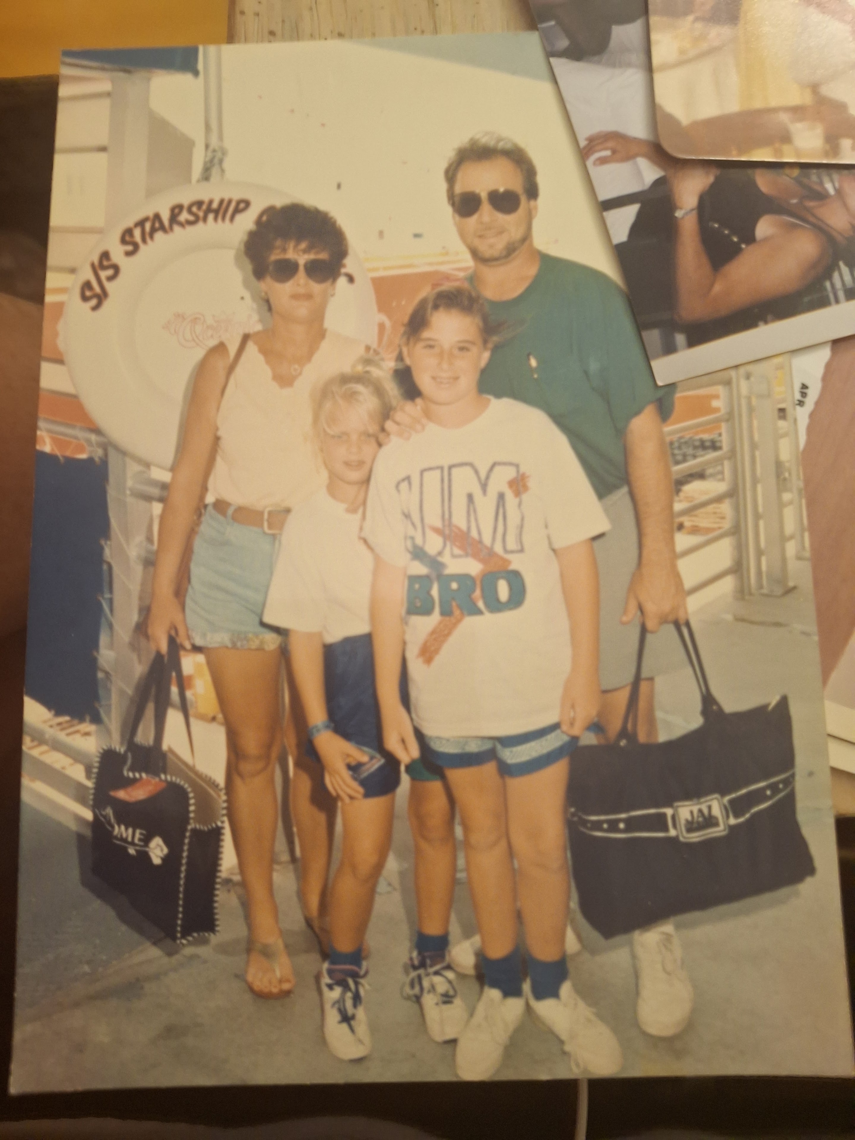 Four people pose together beside a spaceship ride at a theme park while enjoying a day out.