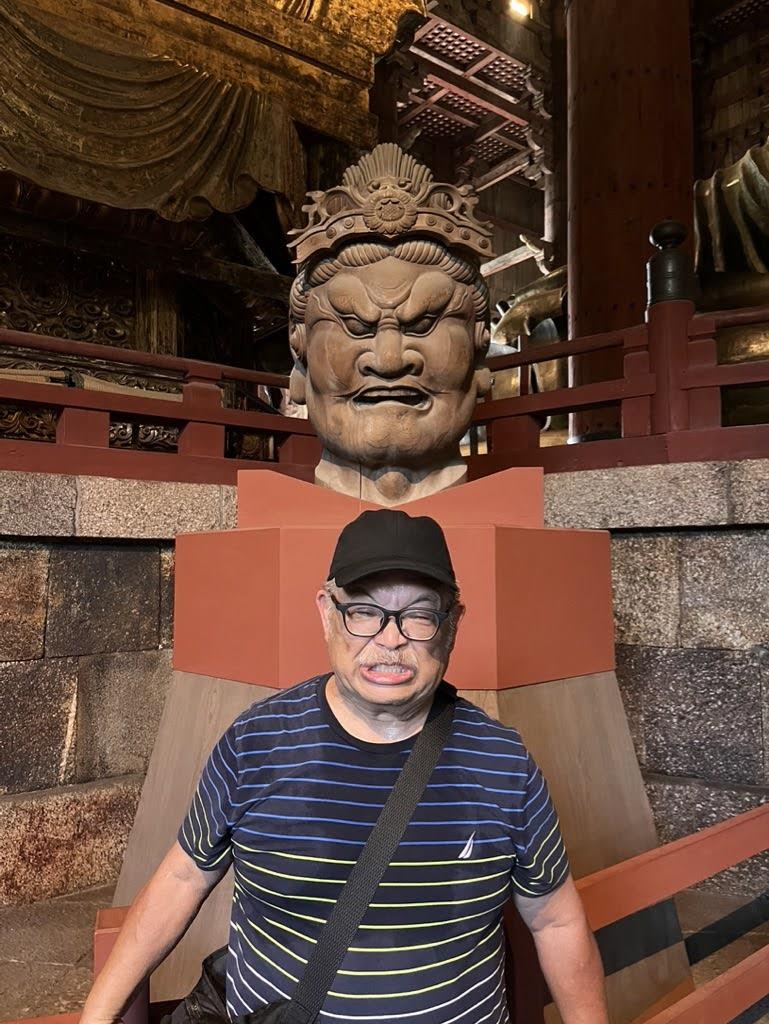 A person stands in front of a big statue at a temple.