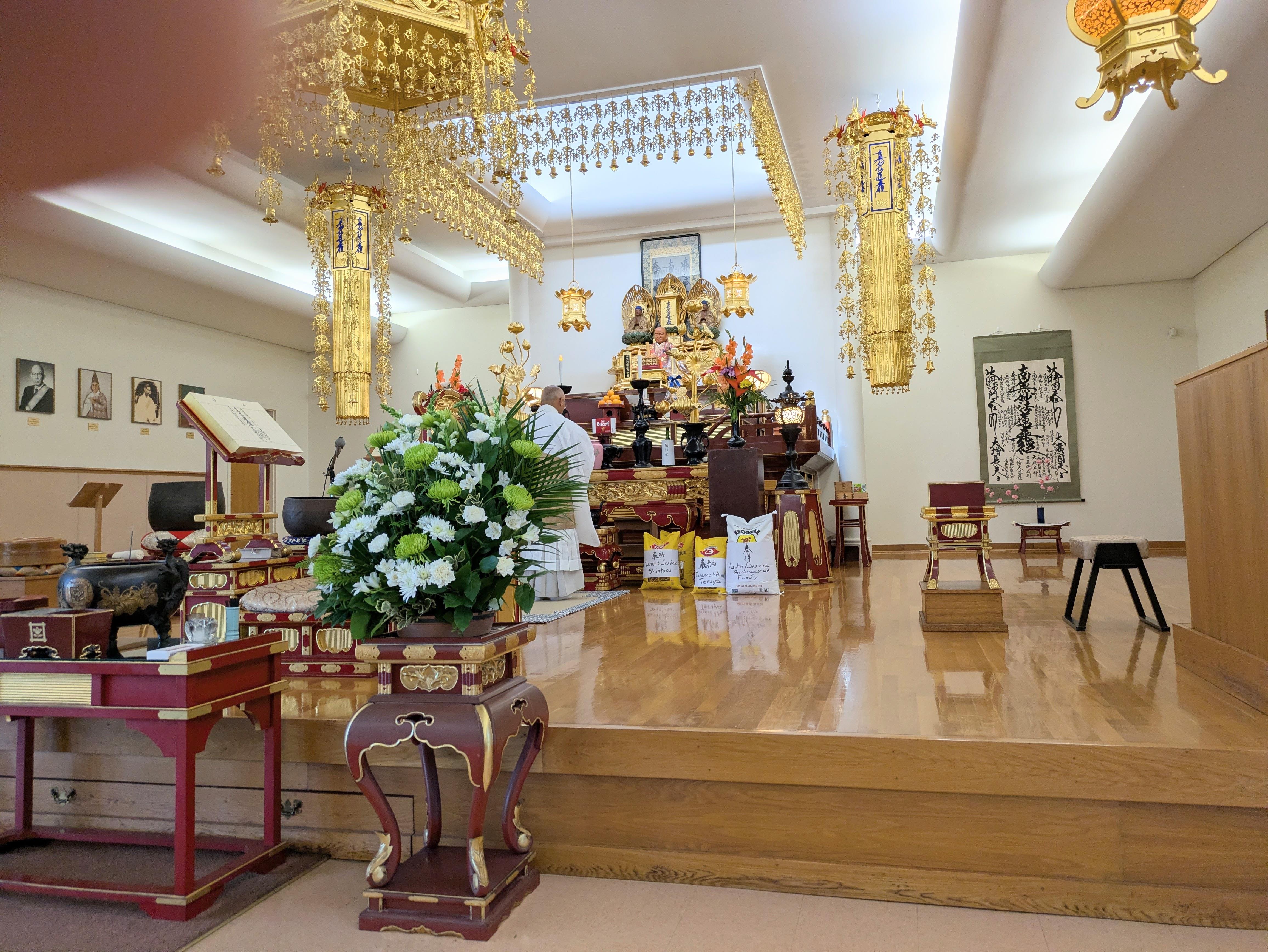 People are preparing offerings in a temple with decorations and flowers present in the space.