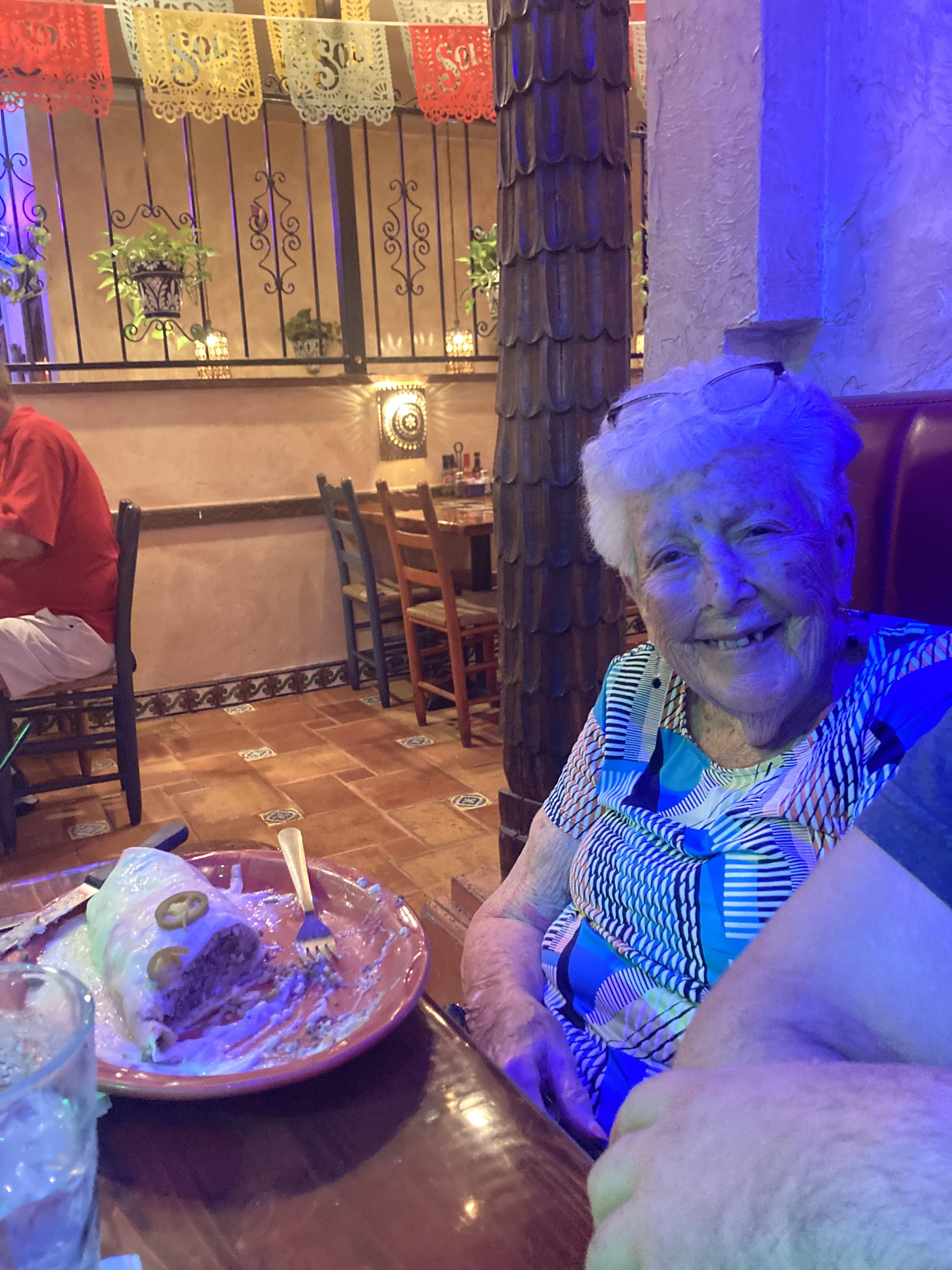 An old woman sitting at a table with food on it