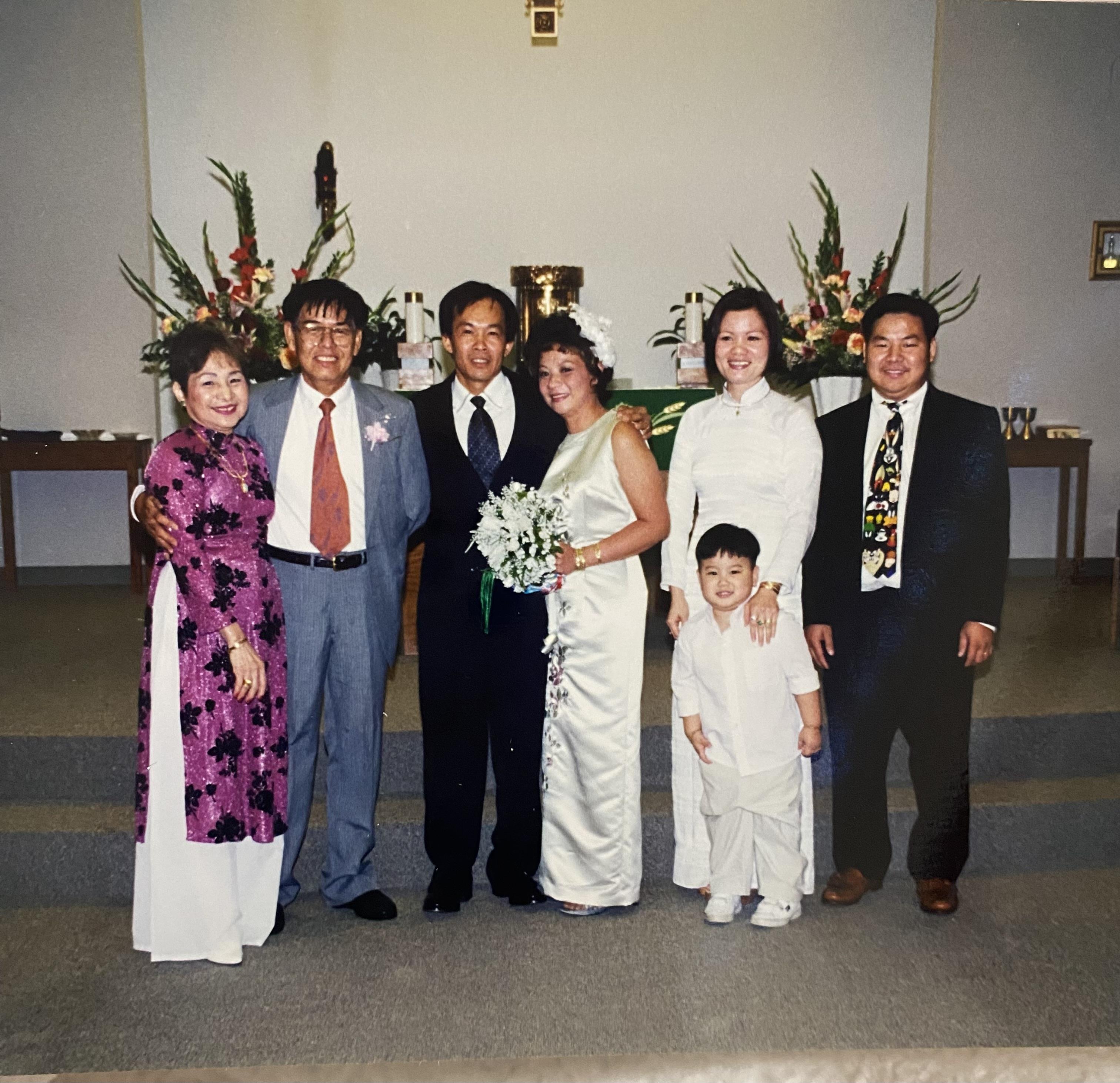 Family stands together for a wedding moment in a decorated hall. Smiles, joy, and good memories.