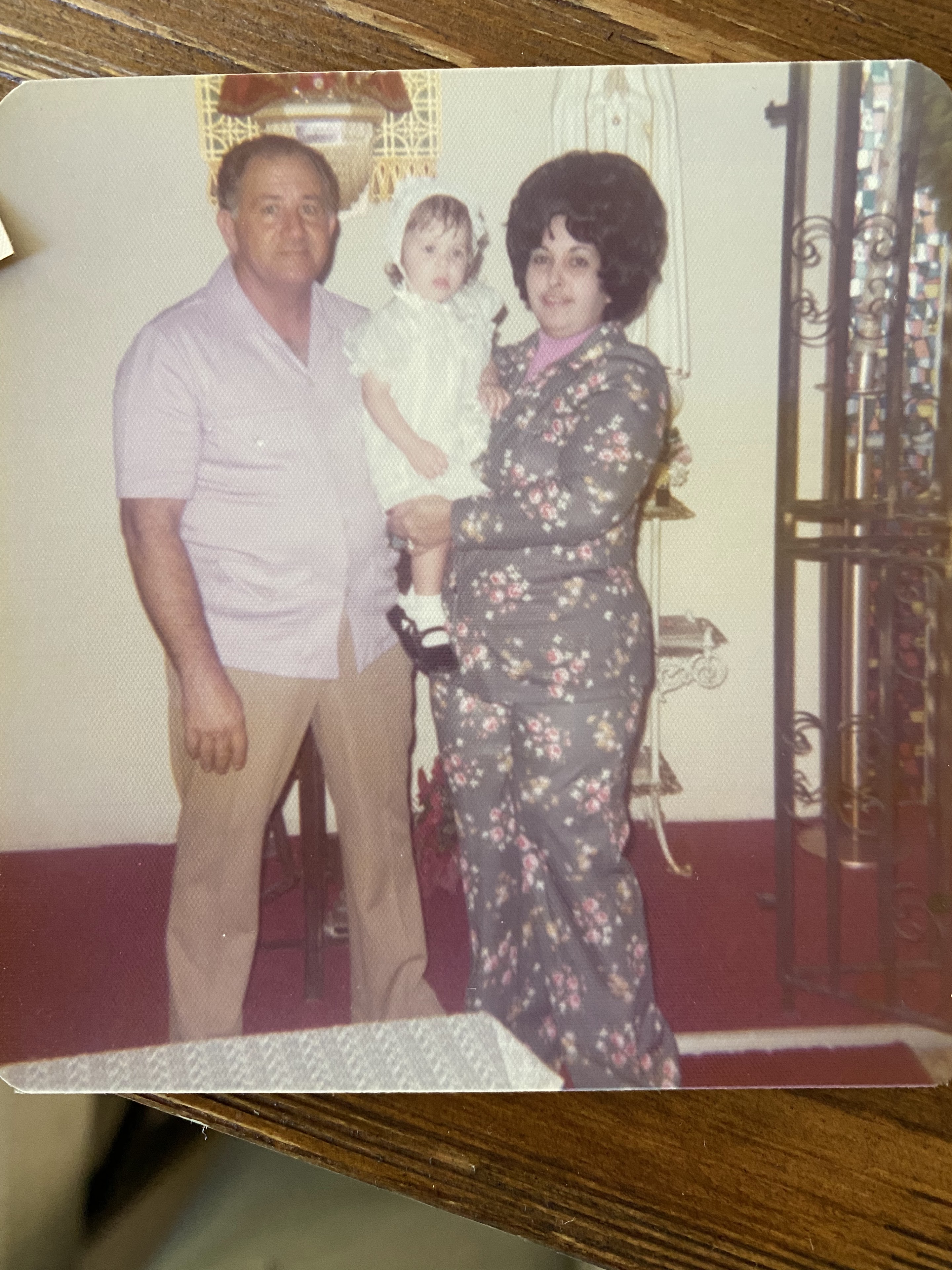 A family stands together in a living room. A man and a woman hold a baby.