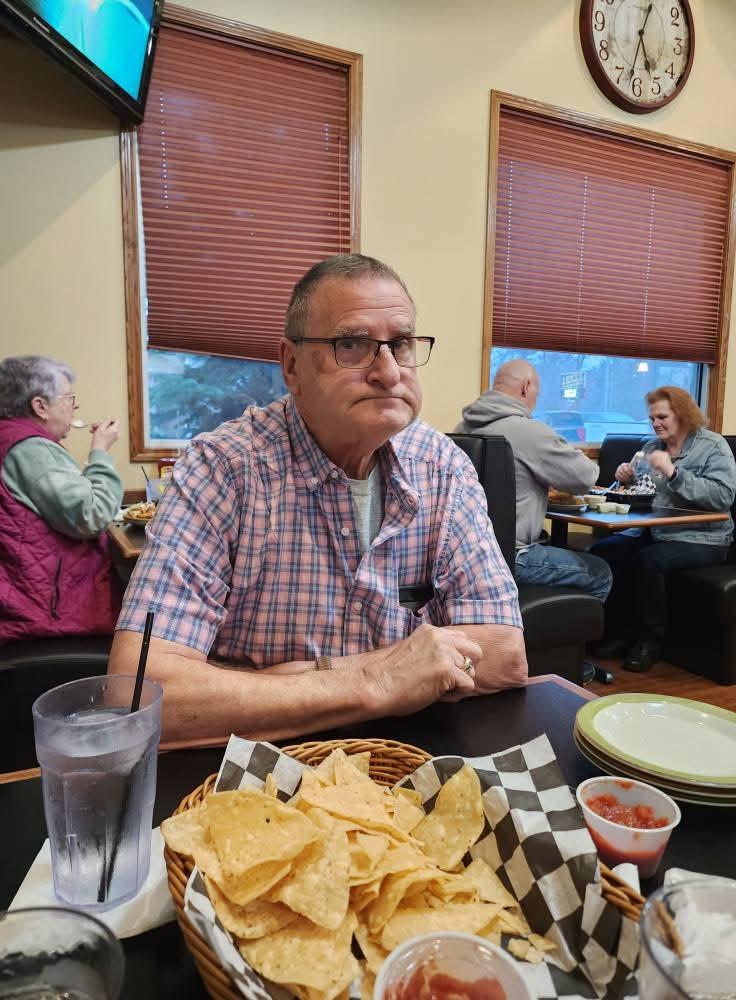 A man sitting at a table with food and a drink