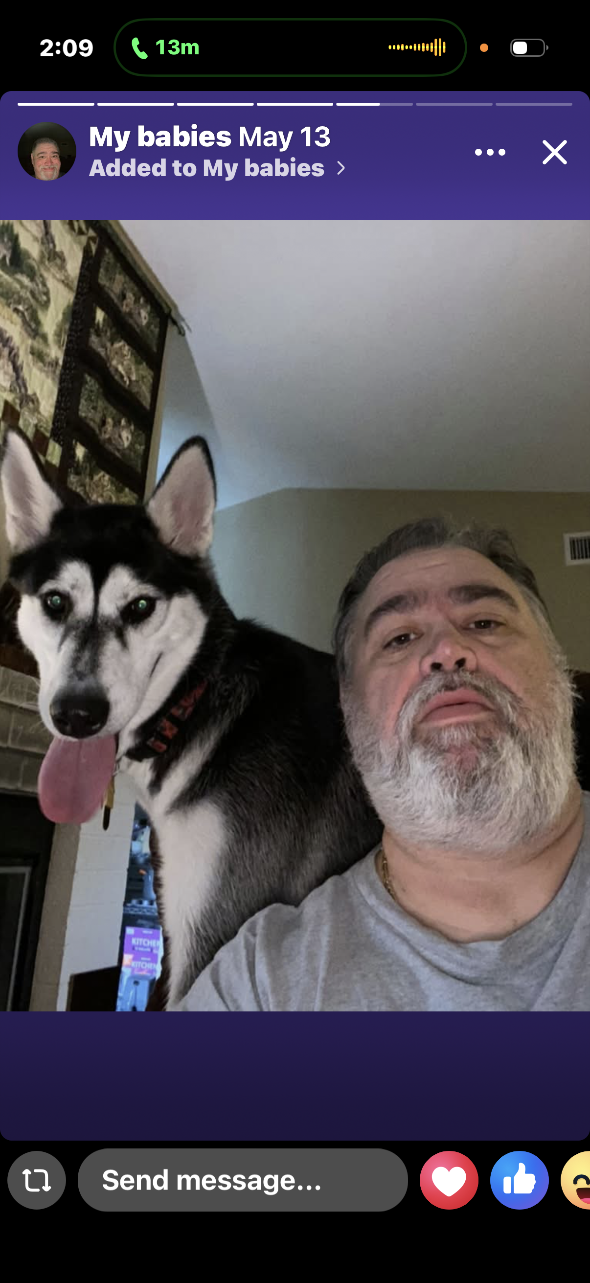 Man and dog pose together at home with a warm smile in a relaxed living room space.