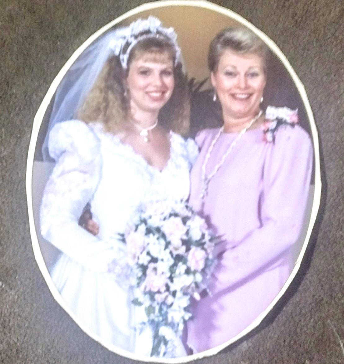 A bride stands beside her mother, both smiling and enjoying a special moment during the wedding.