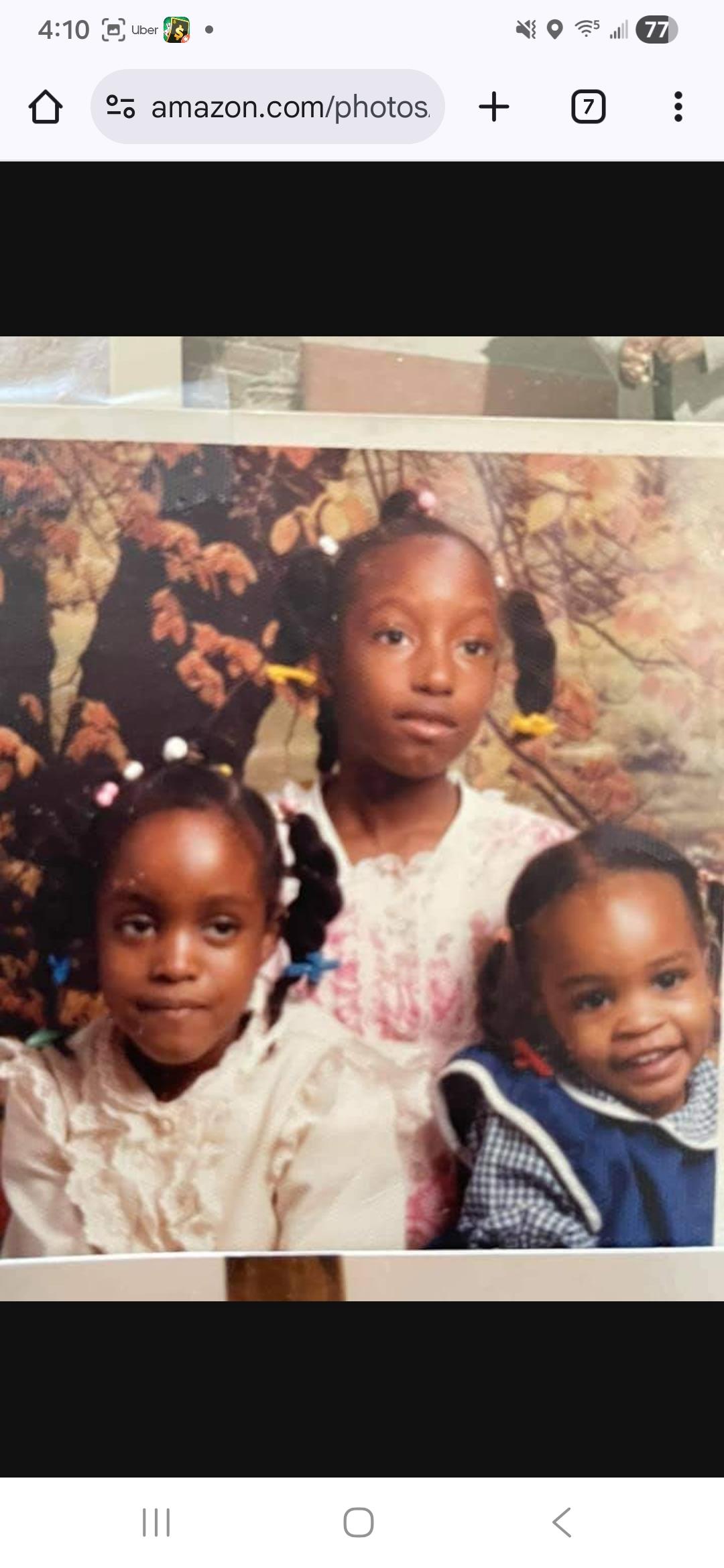 Three children stand together for a portrait in a studio with a backdrop of autumn leaves.