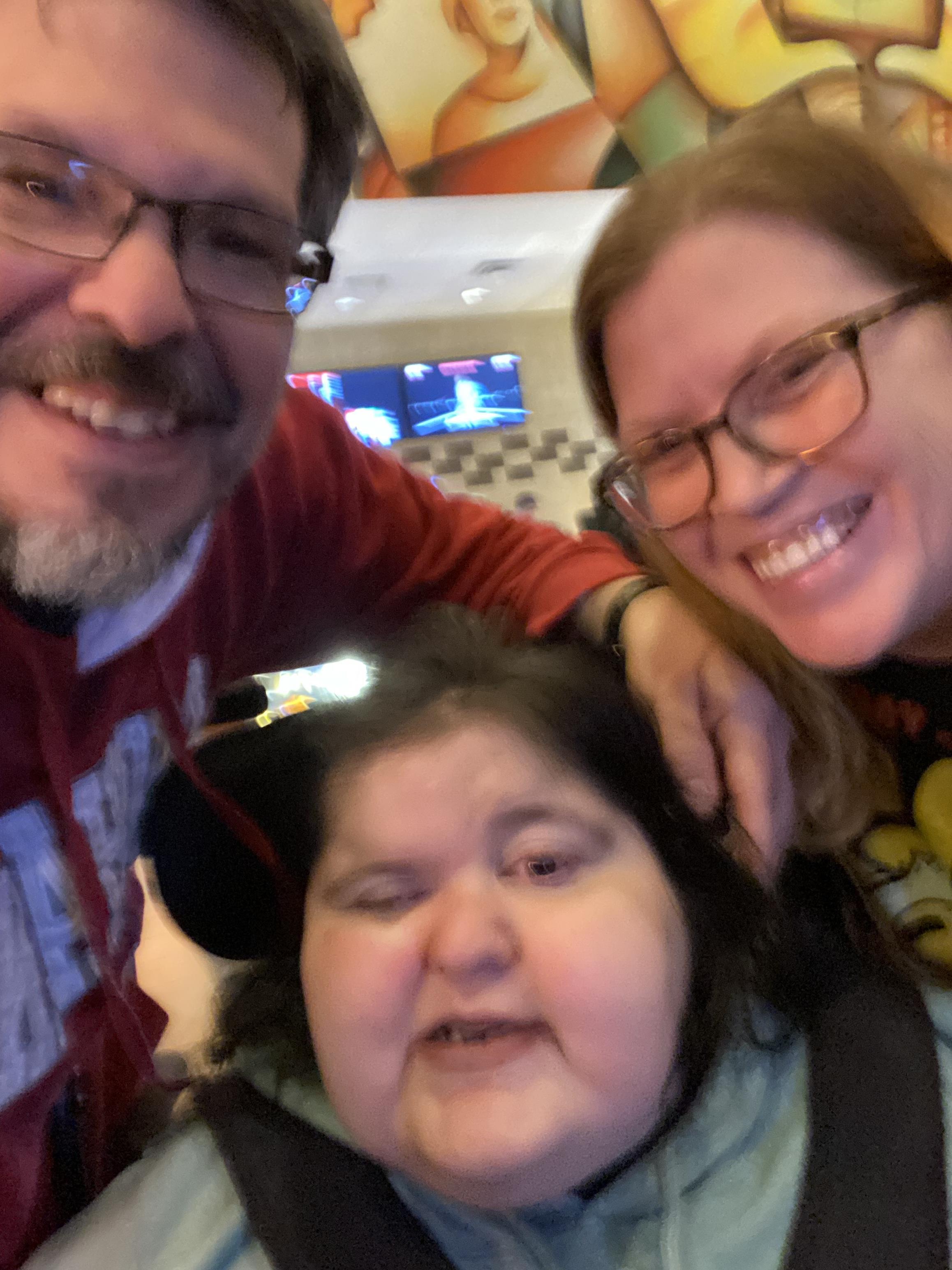 Three family members smile and pose close together in a social setting with warm expressions.