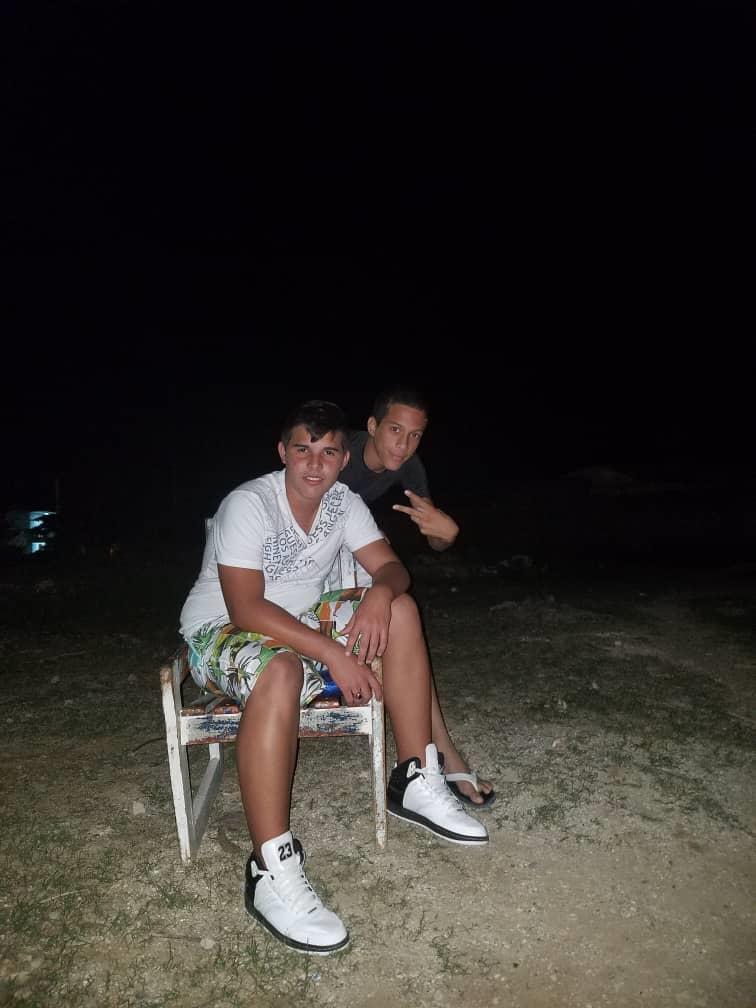 Friends enjoy a night by the beach while sitting on a chair under the stars.