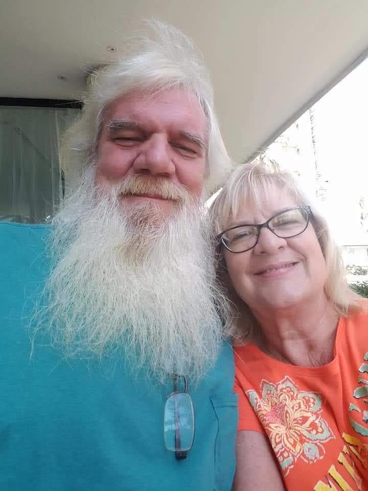 Two people share a smile and take a close selfie together in bright light.